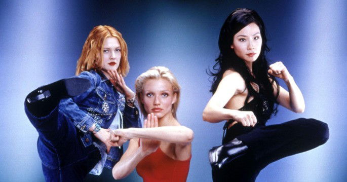 Três mulheres (uma morena, uma ruiva e uma loira) lutando.