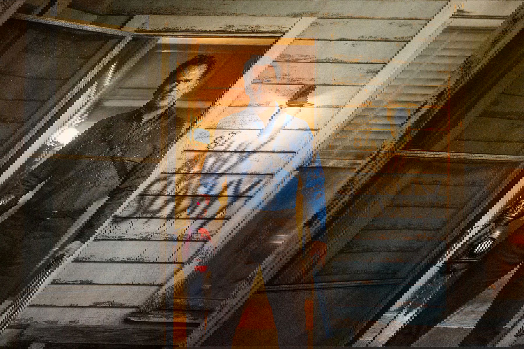 Homem armado, na porta de uma casa.