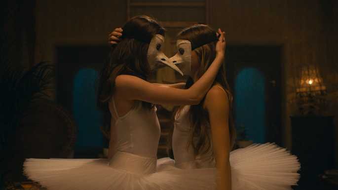Duas bailarinas dançando, abraçadas, e usando máscaras de ave iguais
