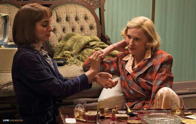 Duas mulheres, uma loira e outra morena, conversando numa sala.