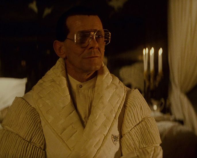 cena amarelada em blade runner exibe Tyrell com roupão e velas ao fundo