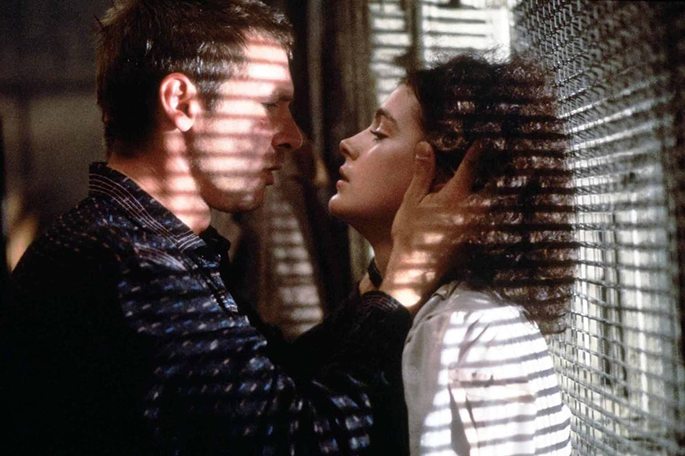 Deckar e Rachel prestes a se beijar em janela que exibe a luz entrando pela grade