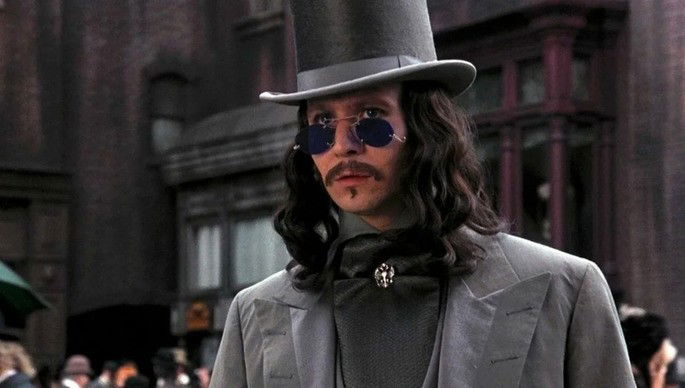 Drácula vestido com roupas antigas, chapéu e óculos escuros.