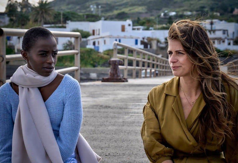 Cena do filme Em busca de mim mostra duas mulheres sentadas ao ar livre com vento no rosto..