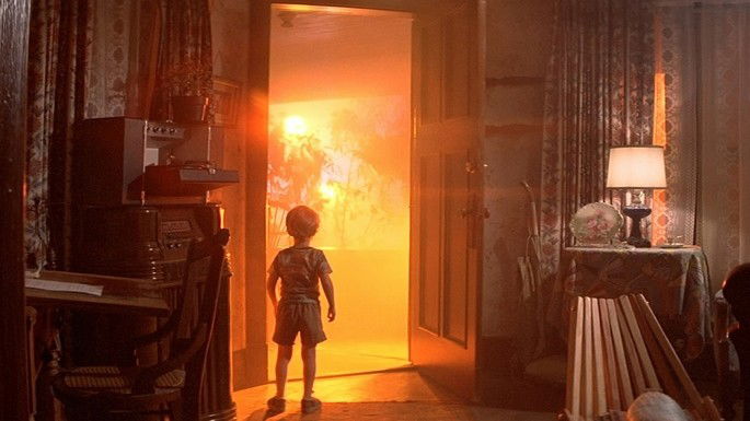 Silhueta de um menino, diante de uma enorme luz laranja.