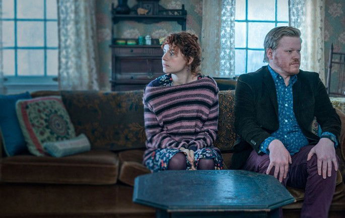 Lucy e Jake sentados no sofá, olhando um para cada lado.