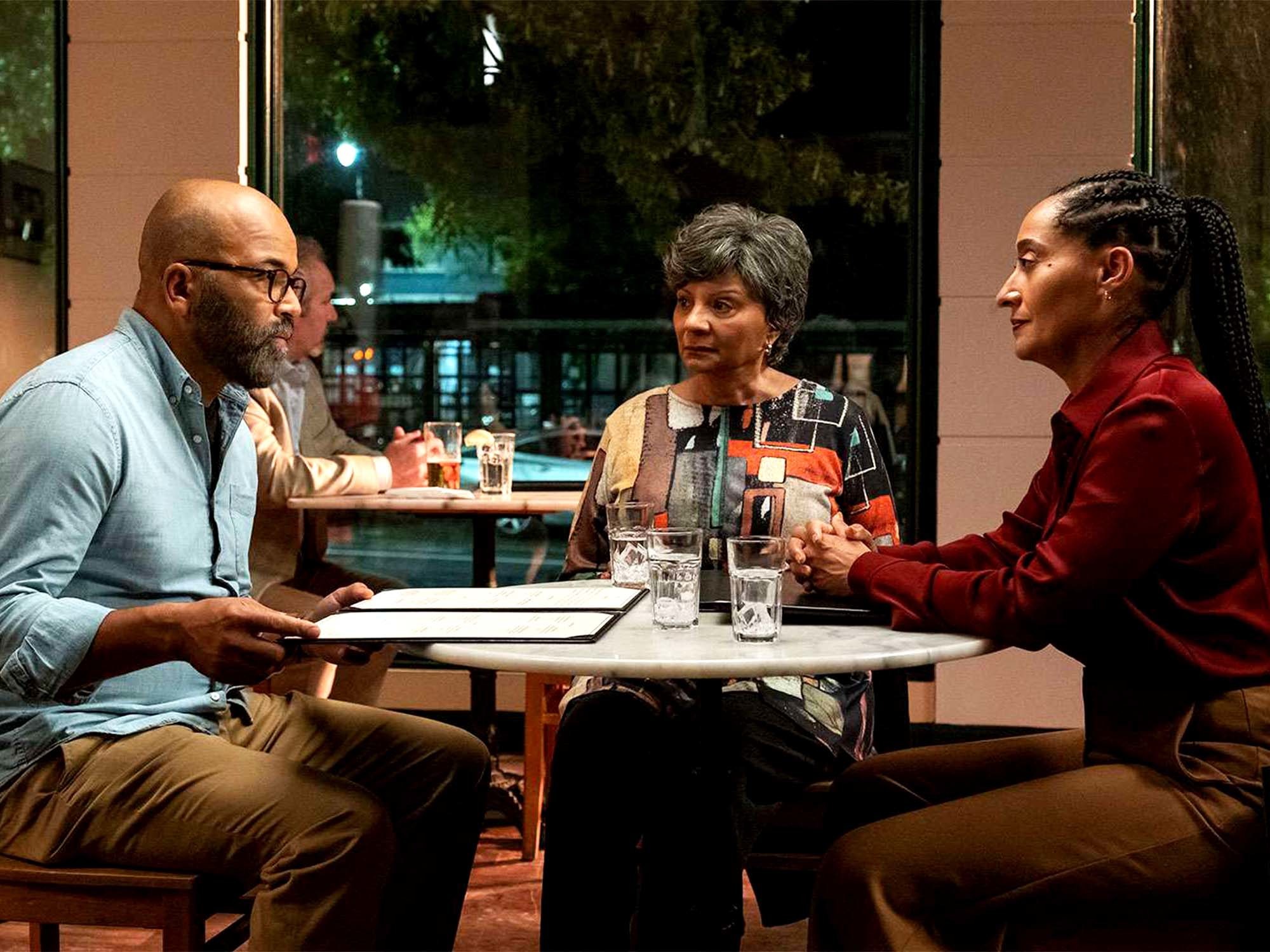 Casal e mulher mais velha, sentados na mesa de um restaurante.