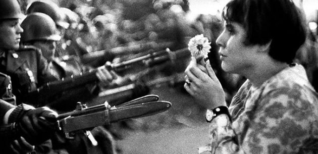 Retrato de mulher nos anos 60 segurando uma flor diante dos militares.