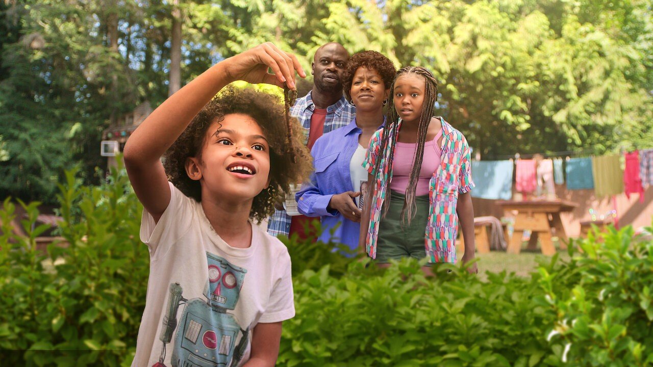 cena do filme Ivy e Bean mostra menina negra em primeiro plano e família atrás