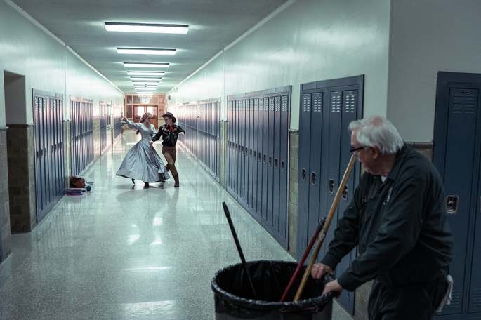 Zelador vendo casal dançando no corredor da escola