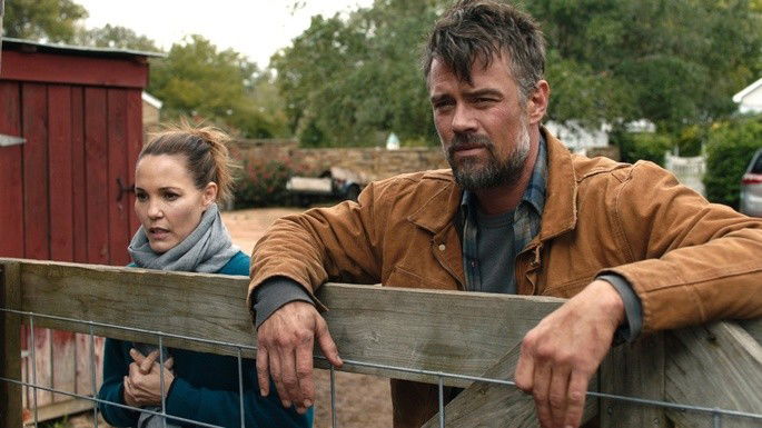 Homem e mulher encostados numa cerca.