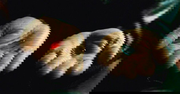 Mãos de Morpheus segurando os comprimidos.