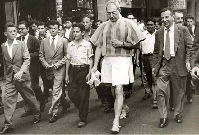 homem caminhando na rua com saia ao redor de transeuntes