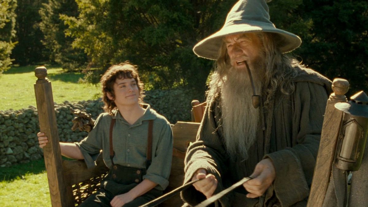 Frodo e Gandalf andando de carroça e rindo.