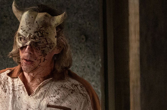 Homem sujo de sangue, usando uma máscara de diabo.