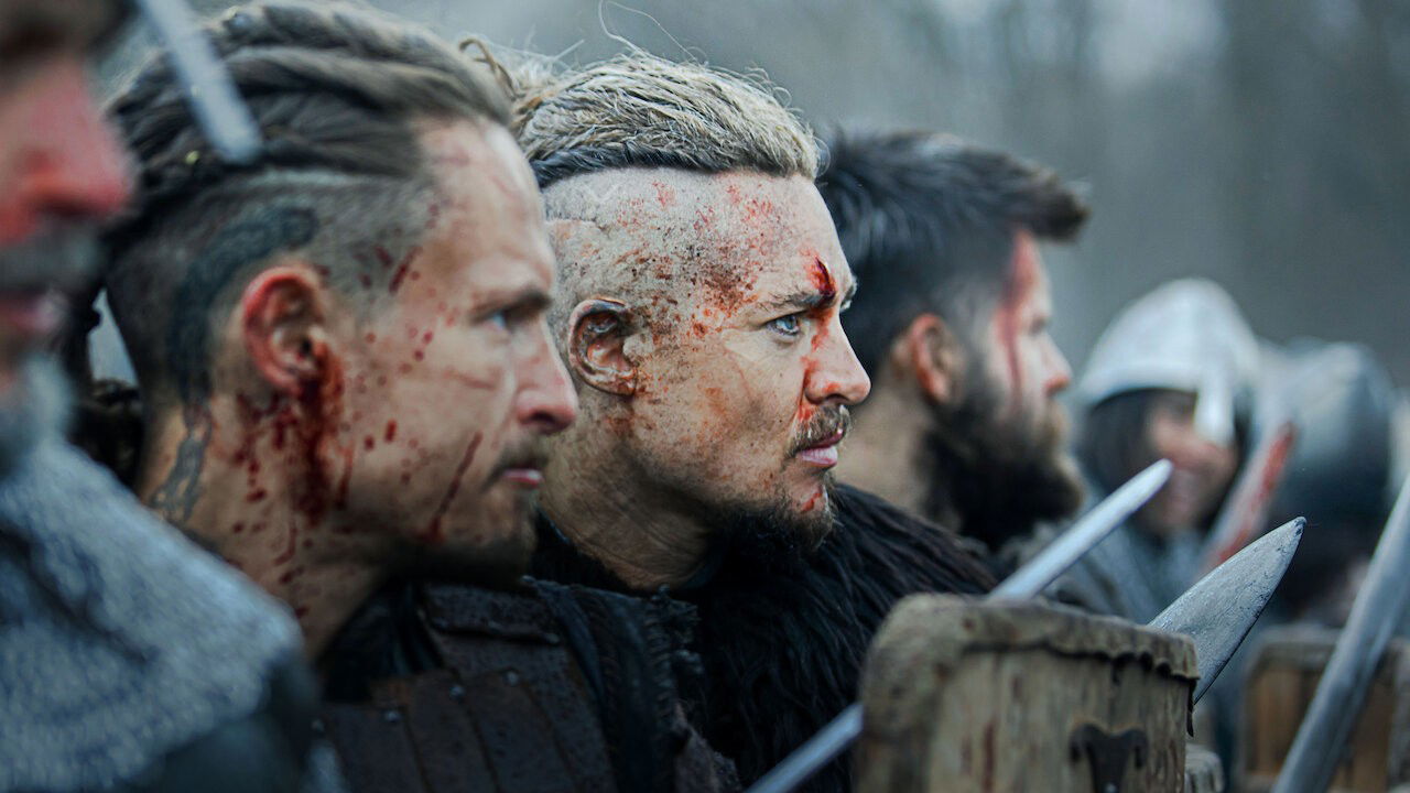 Soldados medievais no campo de batalha, com sangue nos rostos.