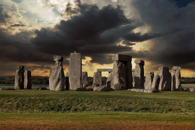 monumento de pedras feito no período neolítico. Pedras dispostas em campo verde com nuvens negras no céu