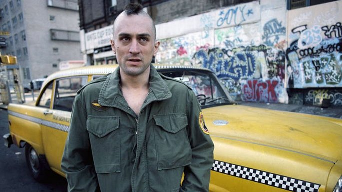 Homem, com cabelo de crista, na frente de um taxi amarelo