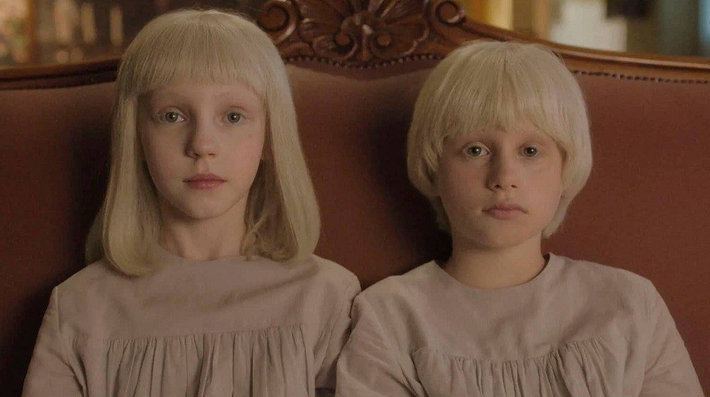 cena do filme Tin e Tina mostra duas crianças albinas sentadas no sofá