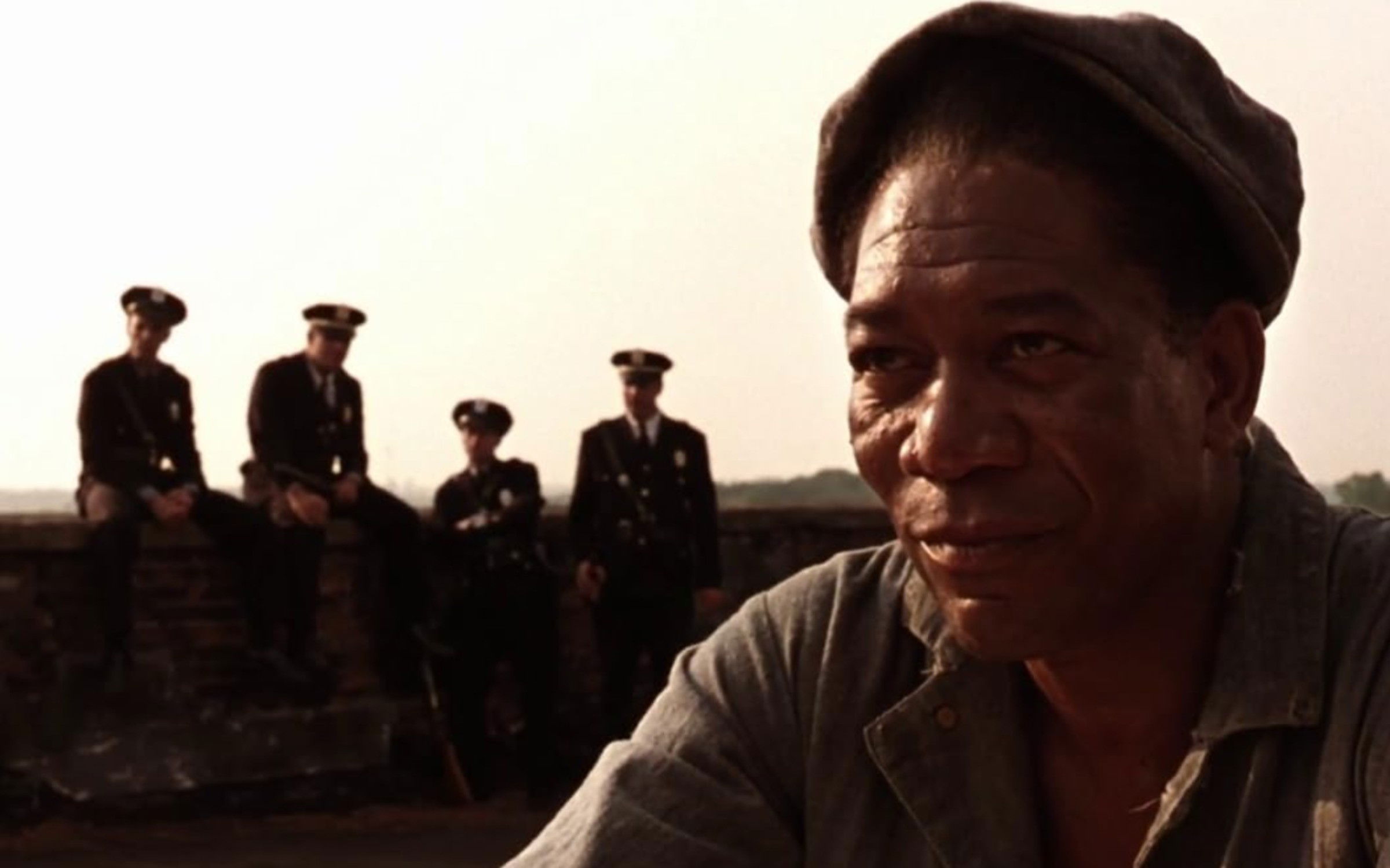 Morgan Freeman em rimeiro plano com policiais ao fundo, fora de foco