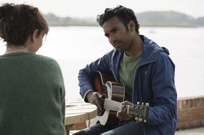 Homem cantando para uma mulher em frente da praia.